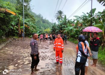 Bhabinkamtibmas Kel.Mafututu Bersama Warga Bersihkan Jalan Akibat Longsor