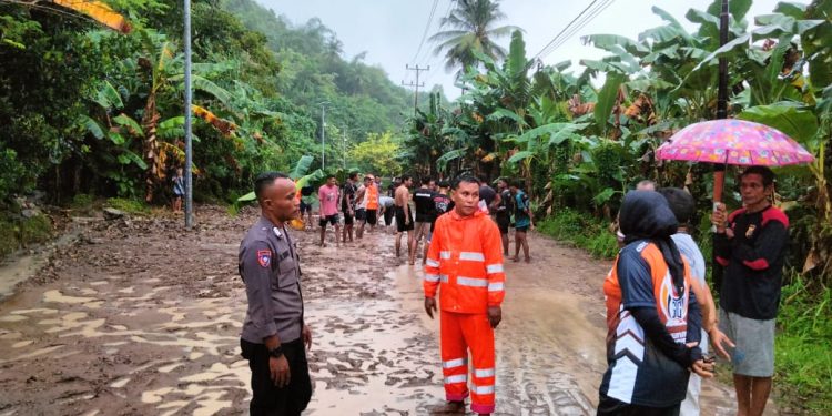 Bhabinkamtibmas Kel.Mafututu Bersama Warga Bersihkan Jalan Akibat Longsor